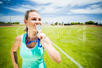 Female athlete kissing his gold medal