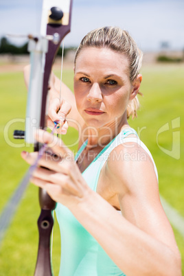 Confident female athlete practicing archery