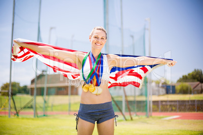 Portrait of female athlete holding up american flag with gold me