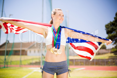 Female athlete holding up american flag with gold medal