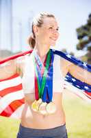 Female athlete holding up american flag with gold medal