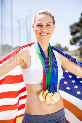 Portrait of happy female athlete holding up american flag with g