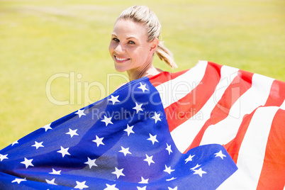 Portrait of happy female athlete holding up american flag with g