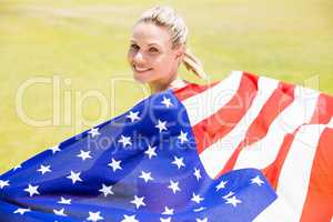 Portrait of happy female athlete holding up american flag with g