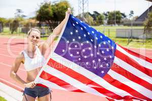 Portrait of happy female athlete holding up american flag