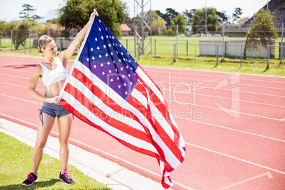 Happy female athlete holding up american flag