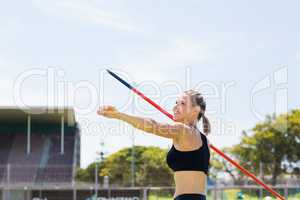 Happy female athlete about to throw a javelin