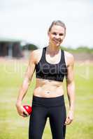 Portrait of happy female athlete holding a shot put ball