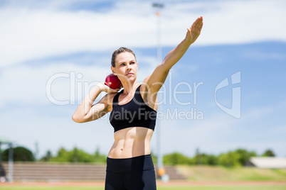 Confident female athlete preparing to throw shot put ball