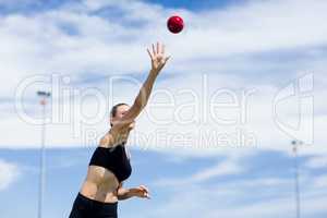 Confident female athlete throwing shot put ball