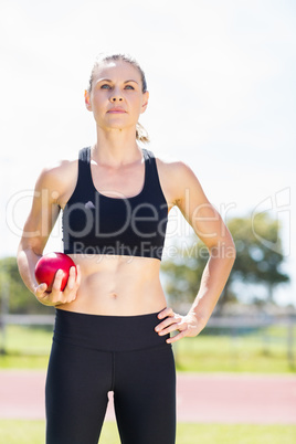 Confident female athlete holding a shot put ball