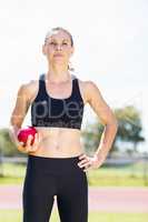 Confident female athlete holding a shot put ball