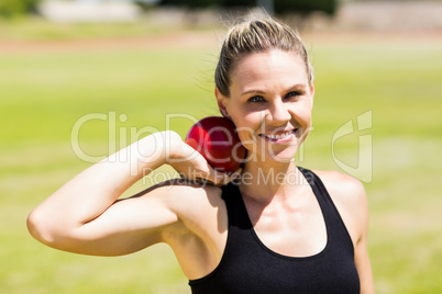 Portrait of happy female athlete preparing to throw shot put bal