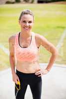 Portrait of female athlete standing with hands on hips