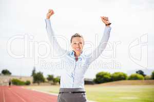 Excited businesswoman standing on the running track