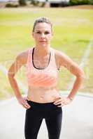 Portrait of female athlete standing with hands on hips