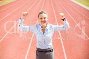 Portrait of excited businesswoman standing on the running track
