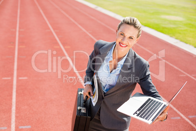 Portrait of happy businesswoman ready to run with a laptop and b