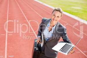 Portrait of happy businesswoman ready to run with a laptop and b