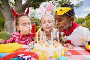 Three little girls blowing together birthday candles