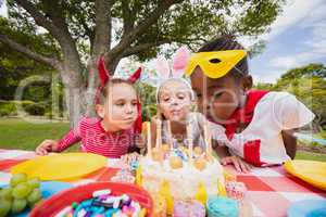 Three little girls blowing together birthday candles