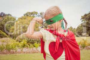 Little girl wearing superhero costume contracting biceps