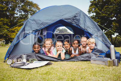 Smiling children lying in the tent together