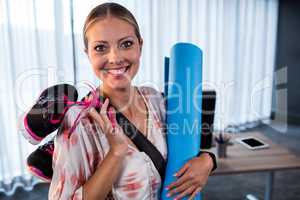 Casual businesswoman with yoga mat and sports shoes
