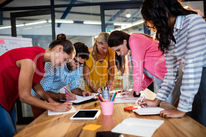 Casual business team writing in notebooks