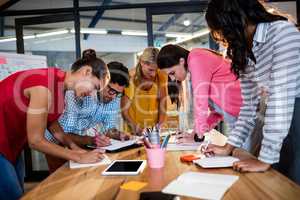 Casual business team writing in notebooks