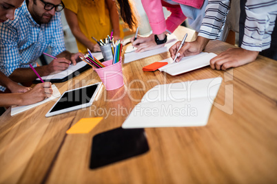 Casual business team writing in notebooks