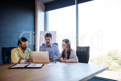 Coworkers working around a table with a laptop