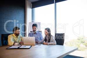 Coworkers working around a table with a laptop