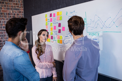 Coworkers interacting front of a board