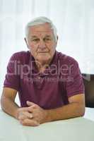 Thoughtful senior man sitting in living room