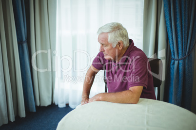 Worried senior man sitting in living room