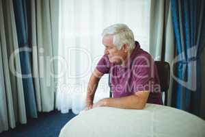 Worried senior man sitting in living room