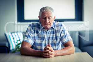 Worried senior man sitting in living room