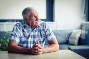 Worried senior man sitting in living room