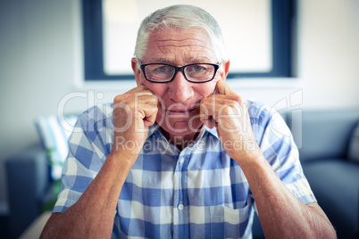 Worried senior man sitting in living room