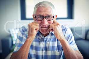 Worried senior man sitting in living room