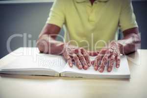 Senior blind man reading a braille book