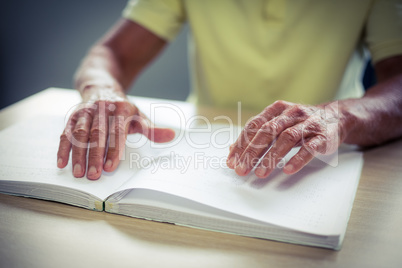 Senior blind man reading a braille book