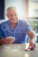 Senior man playing cards in living room