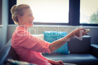 Senior woman changing tv channel
