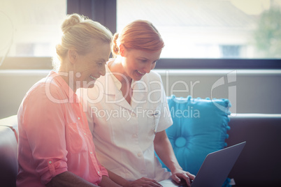 Female nurse and senior woman using laptop