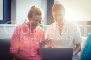Female nurse and senior woman using laptop