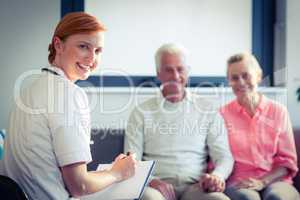 Doctor writing medical report of senior couple