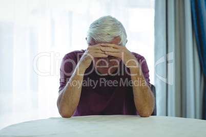 Worried senior man sitting in living room