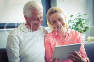 Senior couple smiling while using digital tablet